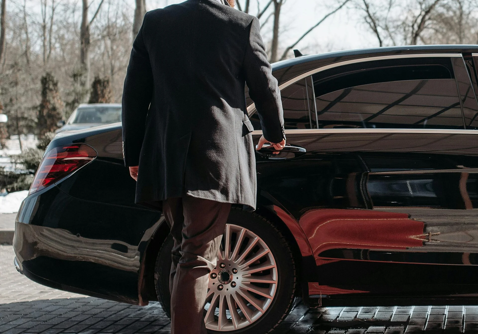 Chauffeur preparing a luxury vehicle for a passenger